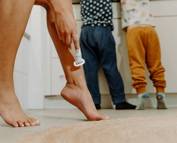 a mom is shaving leg while kids in the bathroom washing hands 